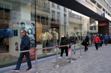 Müşteriler 11 Mayıs 2020 'de Brüksel, Belçika' nın ana ticari caddesi Neuve sokağındaki dükkanlara girmek için kuyruğa girdiler. Yetkililer, 11 Mayıs itibarıyla gereksiz mağazaların kapılarını müşterilere açmasına izin verdiler.. 