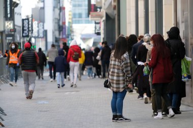 Müşteriler 11 Mayıs 2020 'de Brüksel, Belçika' nın ana ticari caddesi Neuve sokağındaki dükkanlara girmek için kuyruğa girdiler. Yetkililer, 11 Mayıs itibarıyla gereksiz mağazaların kapılarını müşterilere açmasına izin verdiler.. 