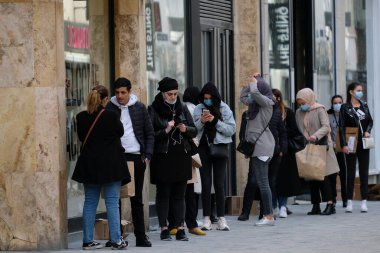 Müşteriler 11 Mayıs 2020 'de Brüksel, Belçika' nın ana ticari caddesi Neuve sokağındaki dükkanlara girmek için kuyruğa girdiler. Yetkililer, 11 Mayıs itibarıyla gereksiz mağazaların kapılarını müşterilere açmasına izin verdiler.. 