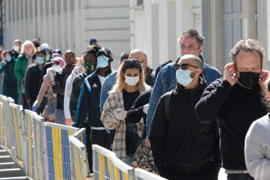 Müşteriler 11 Mayıs 2020 'de Brüksel, Belçika' nın ana ticari caddesi Neuve sokağındaki dükkanlara girmek için kuyruğa girdiler. Yetkililer, 11 Mayıs itibarıyla gereksiz mağazaların kapılarını müşterilere açmasına izin verdiler.. 