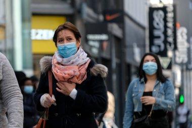 Yüz maskesi takan insanlar, 11 Mayıs 2020 Pazartesi günü Brüksel 'de koronavirüsün, COVID-19' un yayılmasını önlemek için, tecrit sürecinin kademeli kaldırılması sırasında ticari caddede yürürler..