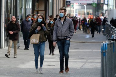 Yüz maskesi takan insanlar, 11 Mayıs 2020 Pazartesi günü Brüksel 'de koronavirüsün, COVID-19' un yayılmasını önlemek için, tecrit sürecinin kademeli kaldırılması sırasında ticari caddede yürürler..