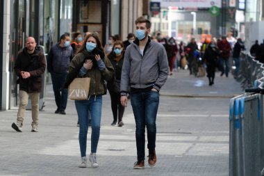 Yüz maskesi takan insanlar, 11 Mayıs 2020 Pazartesi günü Brüksel 'de koronavirüsün, COVID-19' un yayılmasını önlemek için, tecrit sürecinin kademeli kaldırılması sırasında ticari caddede yürürler..