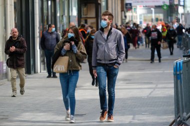 Yüz maskesi takan insanlar, 11 Mayıs 2020 Pazartesi günü Brüksel 'de koronavirüsün, COVID-19' un yayılmasını önlemek için, tecrit sürecinin kademeli kaldırılması sırasında ticari caddede yürürler..