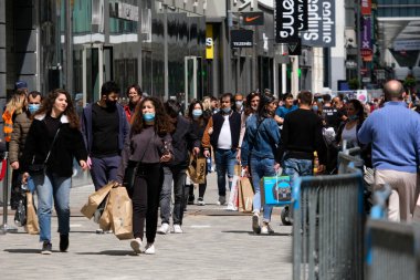 Yüz maskesi takan insanlar, 11 Mayıs 2020 Pazartesi günü Brüksel 'de koronavirüsün, COVID-19' un yayılmasını önlemek için, tecrit sürecinin kademeli kaldırılması sırasında ticari caddede yürürler..