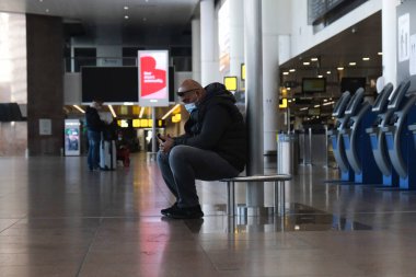 Koronavirüsün yayılmasını önlemek için ağız maskesi takan yolcular, 15 Mayıs 2020 'de Belçika' nın Brüksel kentindeki Brüksel Uluslararası Havalimanı 'ndaki neredeyse boş bir kontrol gişesinde yürüyorlar..