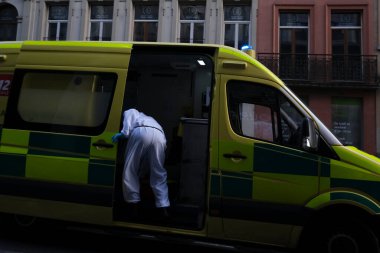 16 Mayıs 2020 'de Brüksel, Belçika' da COVID-19 ile enfekte olduğundan şüphelenilen, kişisel koruma ekipmanı (PPE) taşıyan bir itfaiyeci bir hastayı sedyeyle boşalttı.