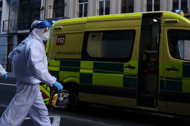 16 Mayıs 2020 'de Brüksel, Belçika' da COVID-19 ile enfekte olduğundan şüphelenilen, kişisel koruma ekipmanı (PPE) taşıyan bir itfaiyeci bir hastayı sedyeyle boşalttı.