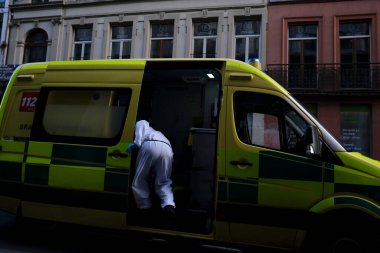 16 Mayıs 2020 'de Brüksel, Belçika' da COVID-19 ile enfekte olduğundan şüphelenilen, kişisel koruma ekipmanı (PPE) taşıyan bir itfaiyeci bir hastayı sedyeyle boşalttı.