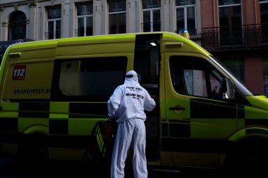 16 Mayıs 2020 'de Brüksel, Belçika' da COVID-19 ile enfekte olduğundan şüphelenilen, kişisel koruma ekipmanı (PPE) taşıyan bir itfaiyeci bir hastayı sedyeyle boşalttı.