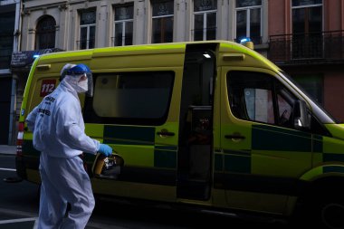 16 Mayıs 2020 'de Brüksel, Belçika' da COVID-19 ile enfekte olduğundan şüphelenilen, kişisel koruma ekipmanı (PPE) taşıyan bir itfaiyeci bir hastayı sedyeyle boşalttı.