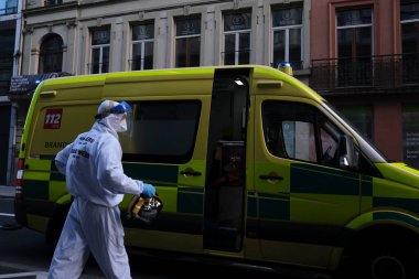 16 Mayıs 2020 'de Brüksel, Belçika' da COVID-19 ile enfekte olduğundan şüphelenilen, kişisel koruma ekipmanı (PPE) taşıyan bir itfaiyeci bir hastayı sedyeyle boşalttı.