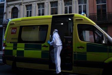 16 Mayıs 2020 'de Brüksel, Belçika' da COVID-19 ile enfekte olduğundan şüphelenilen, kişisel koruma ekipmanı (PPE) taşıyan bir itfaiyeci bir hastayı sedyeyle boşalttı.