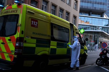 16 Mayıs 2020 'de Brüksel, Belçika' da COVID-19 ile enfekte olduğundan şüphelenilen, kişisel koruma ekipmanı (PPE) taşıyan bir itfaiyeci bir hastayı sedyeyle boşalttı.