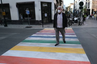 Ağız maskesi takan bir yaya 16 Mayıs 2020 'de Brüksel, Belçika' da gökkuşağı boyalı yaya geçidinde yürüyor.