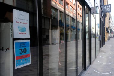 8 Mayıs 2020 'de Brüksel, Belçika' daki covid-19 salgını sırasında müşterilere perakende mağazasının girişinde alışveriş yaparken toplumsal mesafeli olmayı tavsiye eden bir poster.