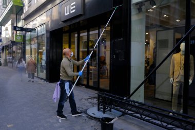  11 Mayıs 2020 'de Brüksel, Belçika' daki gereksiz mağazaların yeniden açılmasından önce bir çalışan bir mağazanın camını temizler..