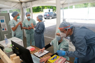 Sağlık personeli, 5 Mayıs 2020 'de Belçika' daki Liege Üniversitesi Hastanesi 'ndeki COVID-19 test sahasında bulunan insanları kontrol ediyor..