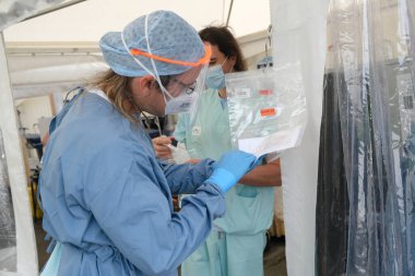 Sağlık personeli, 5 Mayıs 2020 'de Belçika' daki Liege Üniversitesi Hastanesi 'ndeki COVID-19 test sahasında bulunan insanları kontrol ediyor..