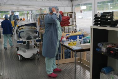 Sağlık personeli, 5 Mayıs 2020 'de Belçika' daki Liege Üniversitesi Hastanesi 'ndeki COVID-19 test sahasında bulunan insanları kontrol ediyor..