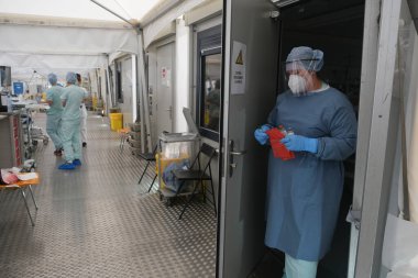 Sağlık personeli, 5 Mayıs 2020 'de Belçika' daki Liege Üniversitesi Hastanesi 'ndeki COVID-19 test sahasında bulunan insanları kontrol ediyor..