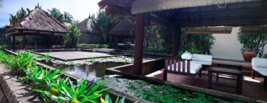 Okyanusta dinlenmek ve dinlenmek için açık alan bungalovları. Bungalovların etrafında çiçek açan nilüferlerle dolu havuzlar var..