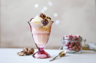 Ballı ve cevizli dondurma. Ceviz ve balla süslenmiş, dondurmayla servis edilmiş. Masanın üzerinde kurutulmuş çilek, kaşık ve ceviz dolu bir kavanoz var..