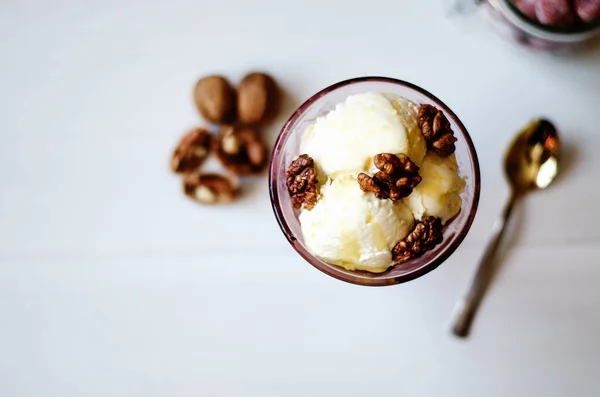 Creamy ice cream with honey and walnuts. Served in a bowl with ice cream, garnished with walnuts and honey. On the table is a jar with dried strawberries, a spoon and a walnut. — Stock Photo, Image