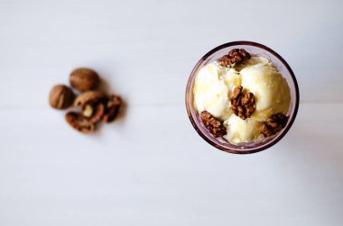 Ballı ve cevizli dondurma. Ceviz ve balla süslenmiş, dondurmayla servis edilmiş. Masanın üstünde ceviz ve dondurma var..