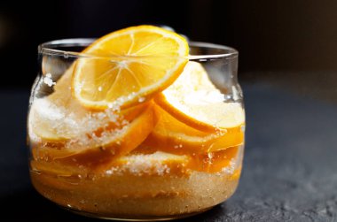 Karamsar. Gıda siyah arka plan. Limon dilimleri cam bir kavanoza doldurulur ve şeker serpiştirilir. Çay seremonisi için limon topluyorum. Yakın plan. Boşluğu kopyala