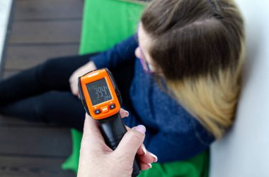 Bir ergende yüksek sıcaklık koronavirüs karantinası. Yüksek ısı göstergeleriyle birlikte elektronik medikal termometre. Evde kalmak için. Önleyici önlemler. Tehlike. Karantina süratle yayıldı.