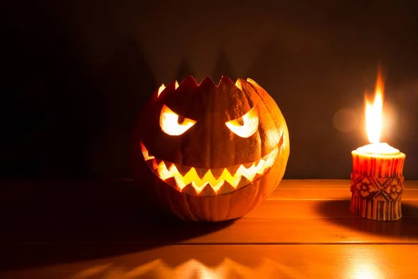 Spooky smiling halloween pumpkin with burning fire candle flame
