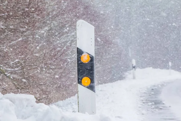 Weiße eisglatte Winterstraße mit Schneeflocken Schneesturm an Reflektorsäule — Stockfoto