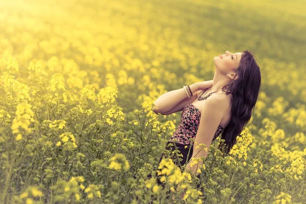 Mooie vrouw in de weide van de gele bloemen met hoofd omhoog — Stockfoto