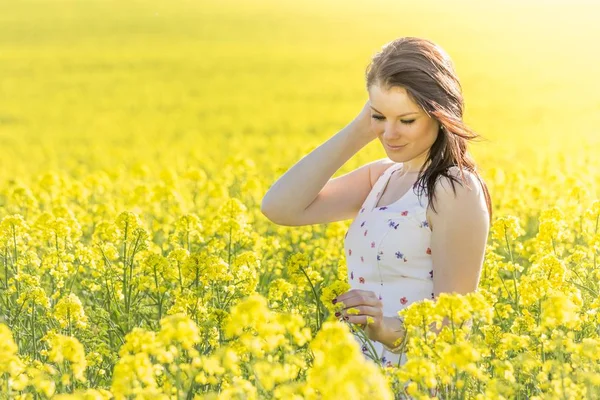 Beautiful young woman with flower in summer meadow looking down — Stock Photo, Image