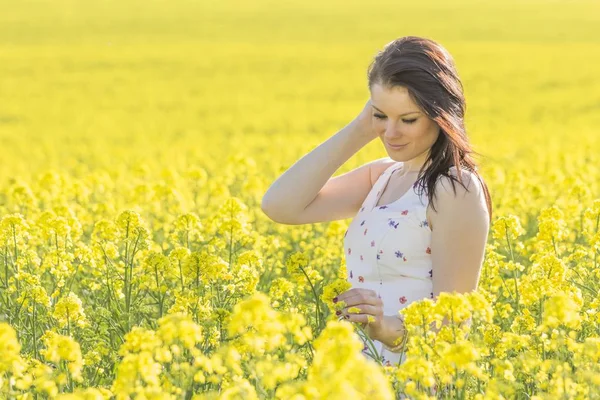 Jeune femme béatifique avec des fleurs dans la prairie d'été regardant vers le bas — Photo