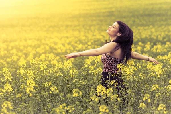 Beautiful woman in meadow of yellow twist from behind — Stock Photo, Image