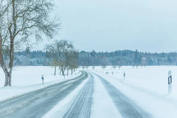 Samotny śliski zimowy ruch drogowy z białym śnieżnym torem — Zdjęcie stockowe