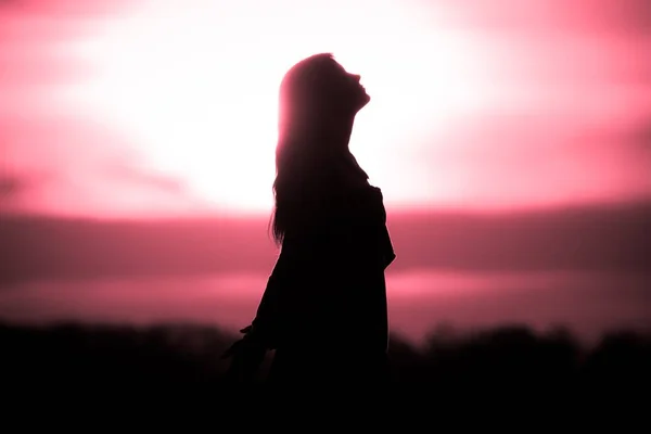 Die Seele der jungen Frau bei der Meditation in der roten Sonne wartet auf die Zukunft Stockbild