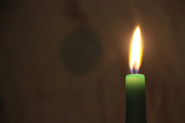 Brilhante vela verde queimando na escuridão — Fotografia de Stock