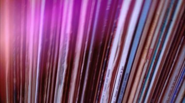 Vinil plak koleksiyonu dikey olarak neon mor parıltıda duruyor.