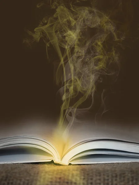 Open book with glowing yellow smoke going from it - magic and mystic concept.