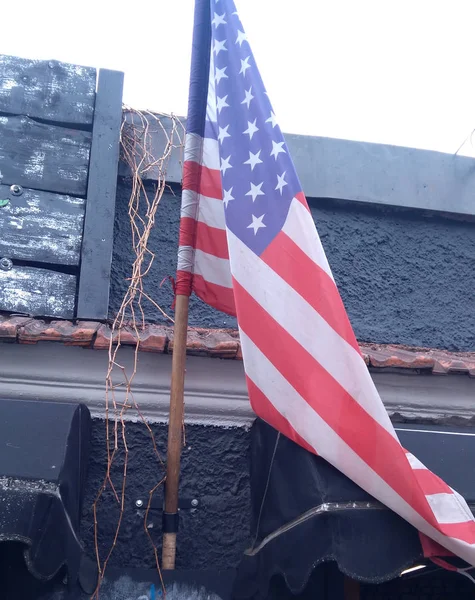 An American flag hanging on a building int the street.
