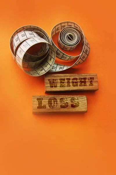 Weight loss words on wooden blocks sign with measure tape on orange background — Stock Photo, Image