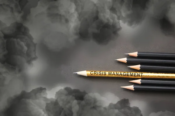 Crisis Management written on pencil composition reminding weapons against heavy clouds. Crisis management or risk assets concept