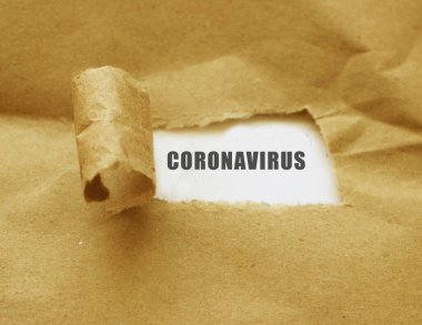 Coronavirus kelimesi yırtık kahverengi kağıdın altında beliriyor - sağlık kavramı