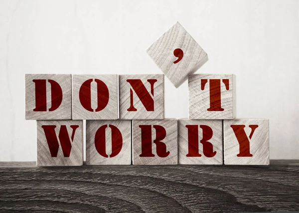 \' Don\'t Worry \' word made of square wooden cubes word on dark oak table. Optimistic concept.