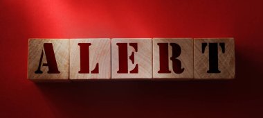Kırmızı arka planda tahta küplerle ilgili ALERT kelimesi. Önleme, dikkat veya acil durum kavramı.