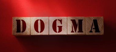 DOGMA kelimesi kırmızı arka planda ahşap harflerden yapılmış. İnanç psikolojisi kavramı.