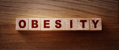 Obezite kelimesi ahşap masa üzerine yazılmış sağlıklı beslenme alışkanlıkları kavramı..